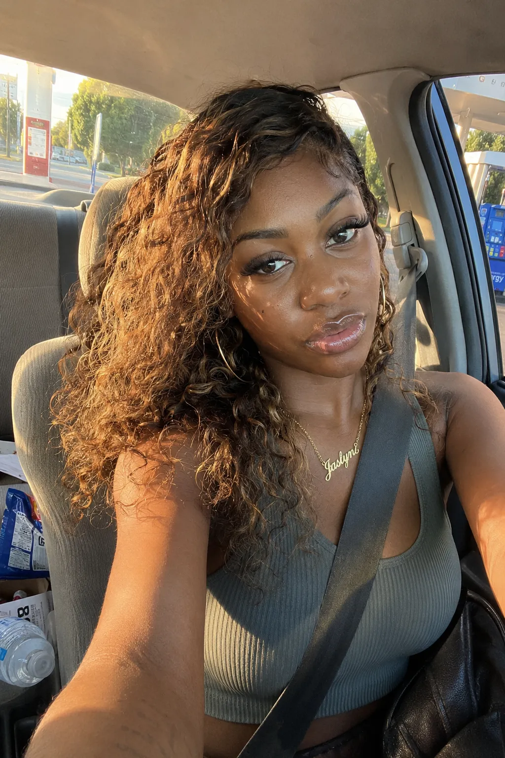 Candid golden-hour selfie in the driver's seat of a car at an ARCO gas station.